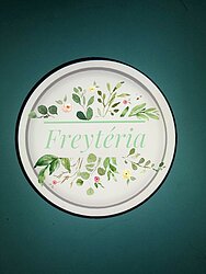 freyteria surrounded by leaves and flowers in a white circle with a green backround
