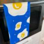 Fried Egg Pattern Full Colour Blue And Yellow Tea Towel, thumbnail 2 of 3