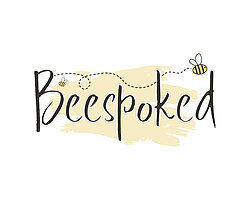 The word Beespoked set against a pale yellow brushstroke background. A small bee with a dotted flight trail weaves through the text.